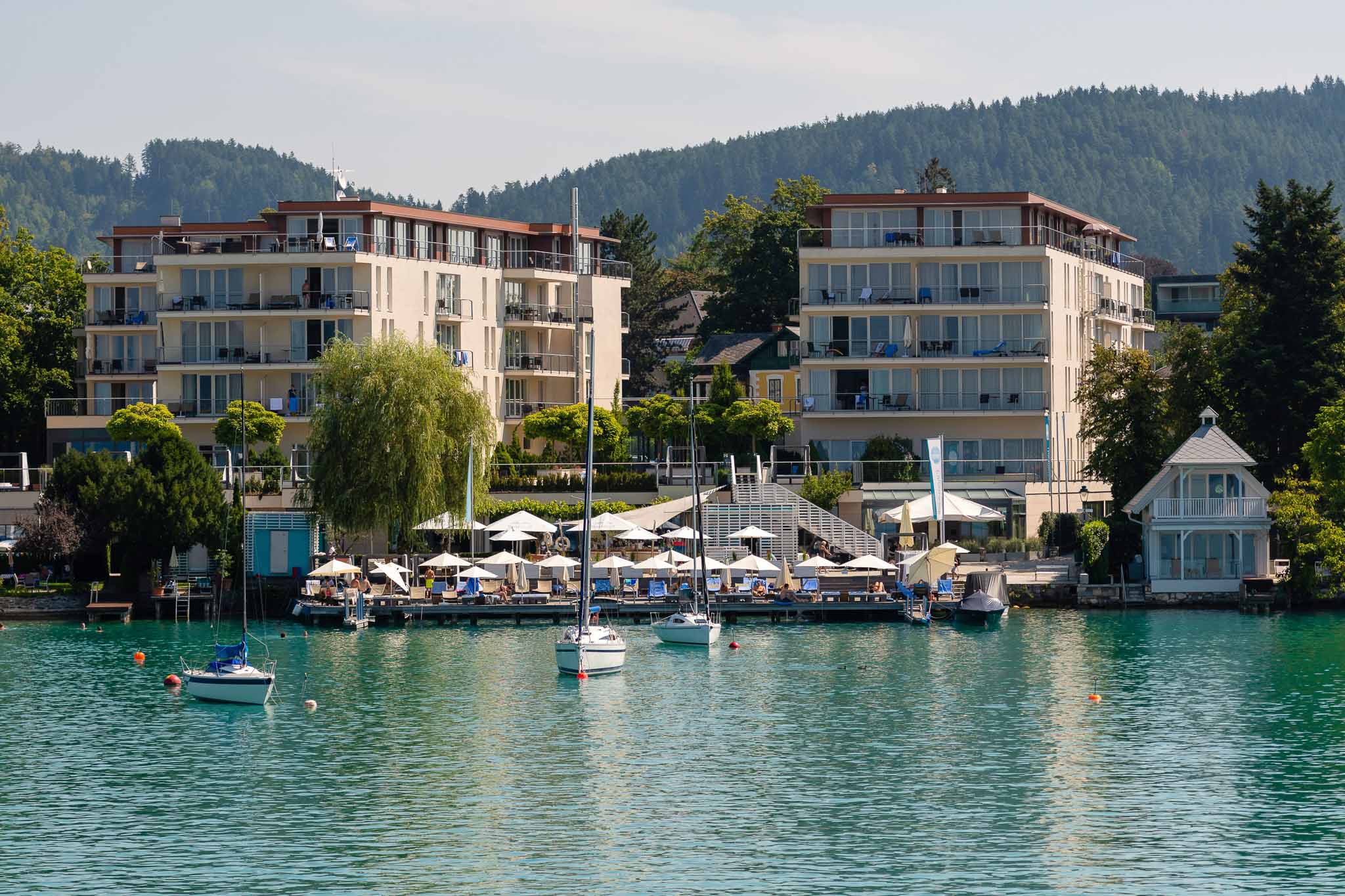 WORTHERSEE, AUSTRIA Great scenery from the boat to the shore line of the lake, beautiful buildings, mountains, forests, highways. Tourists who enjoy a variety of water recreation types.